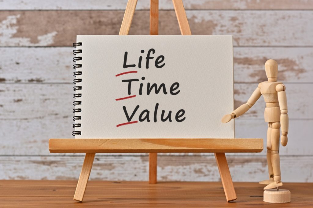 life time valueと書かれたボードの前で、オンボーディングの初期から継続的に得られるメリットについて説明しているビジネスマンを象った人形。